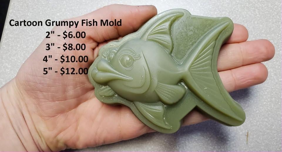 Cartoon grumpy fish mold with large lips and broad fins, cast in green and held in a hand