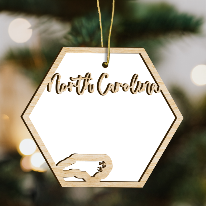 North Carolina hexagon wood ornament on a tree, blank photo panel with the state outline