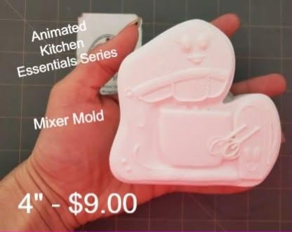 Cartoon stand mixer mold with a smiling face, cast in pink and held in a hand