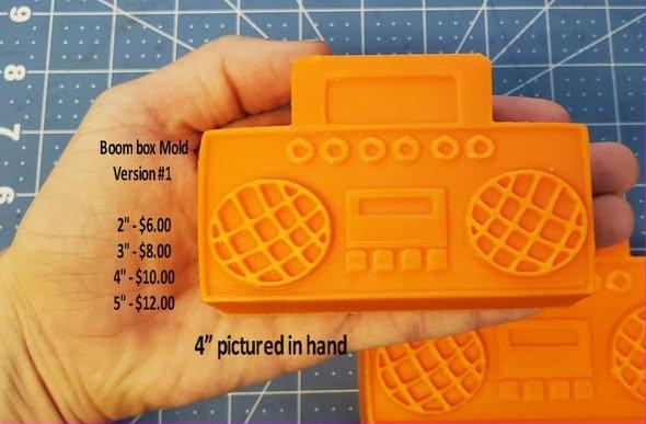 Boom box mold cast in orange, a twin-deck ghetto blaster held in a hand