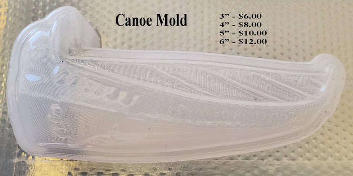 Clear plastic canoe mold on a textured mat, planked hull with diagonal ribbing and a leaf detail at the bow.