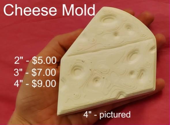 Cheese wedge mold cast in cream and held in a hand, holes sunk into the face