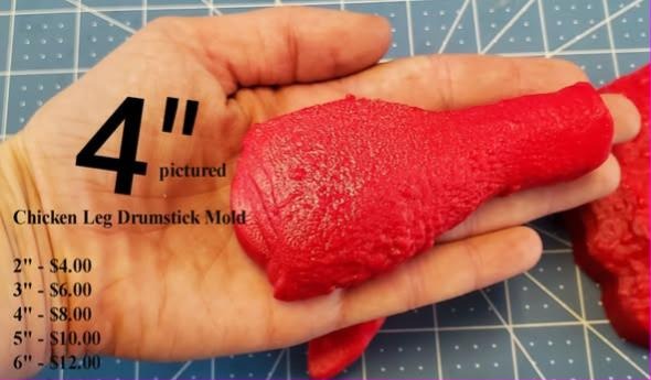 Chicken drumstick mold cast in red and held in a hand, crisped skin texture