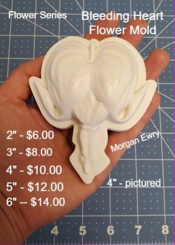 Cream cast bleeding heart flower mold held in a hand, split heart petals with a hanging teardrop.