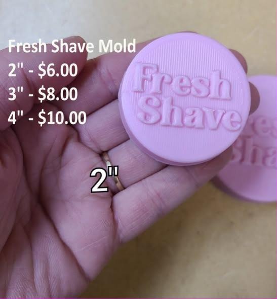 Round Fresh Shave soap puck cast in lilac, distressed brush script lettering, held in hand