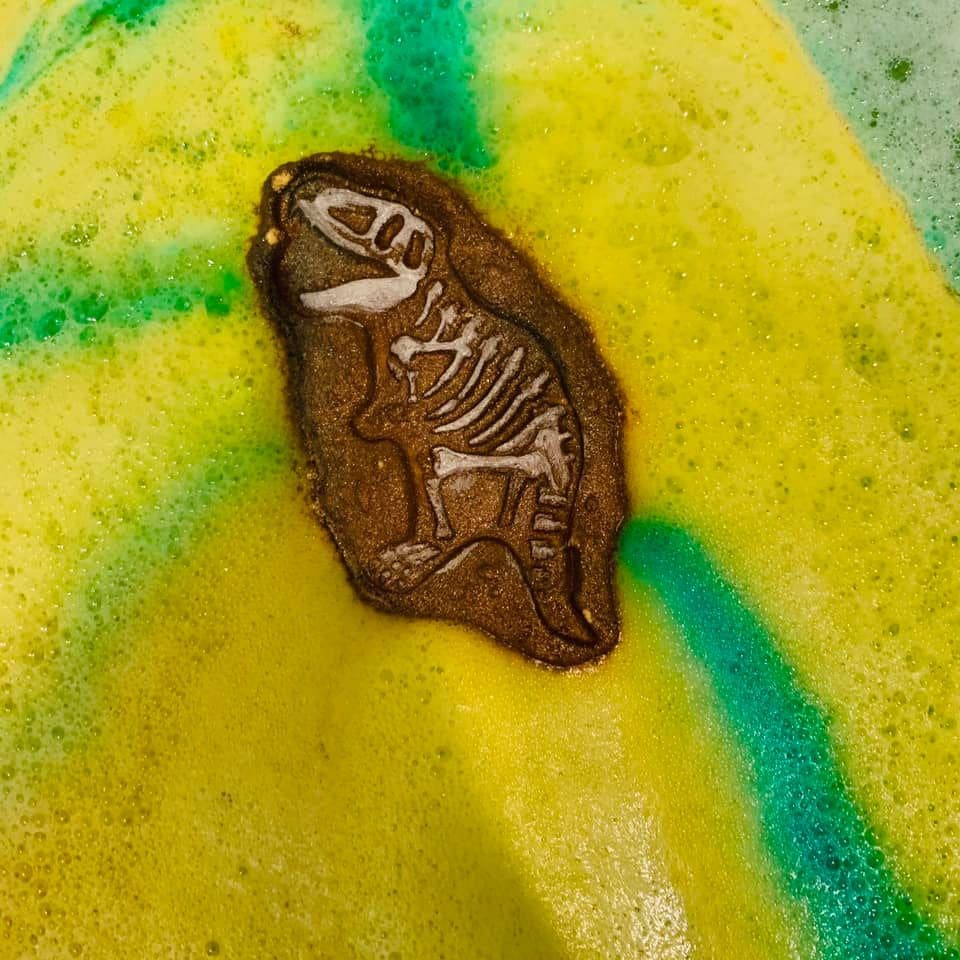 A brown dino fossil cast set into a yellow and green bath bomb