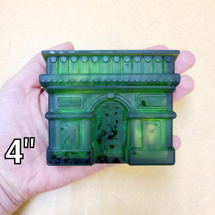 Green resin cast of the Paris arch held in a palm and marked four inches.