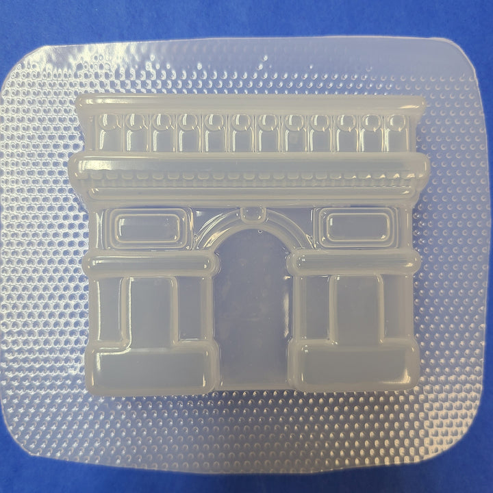 Clear plastic Arc of Paris mold on a dimpled sheet, arch cavity with a columned cornice.