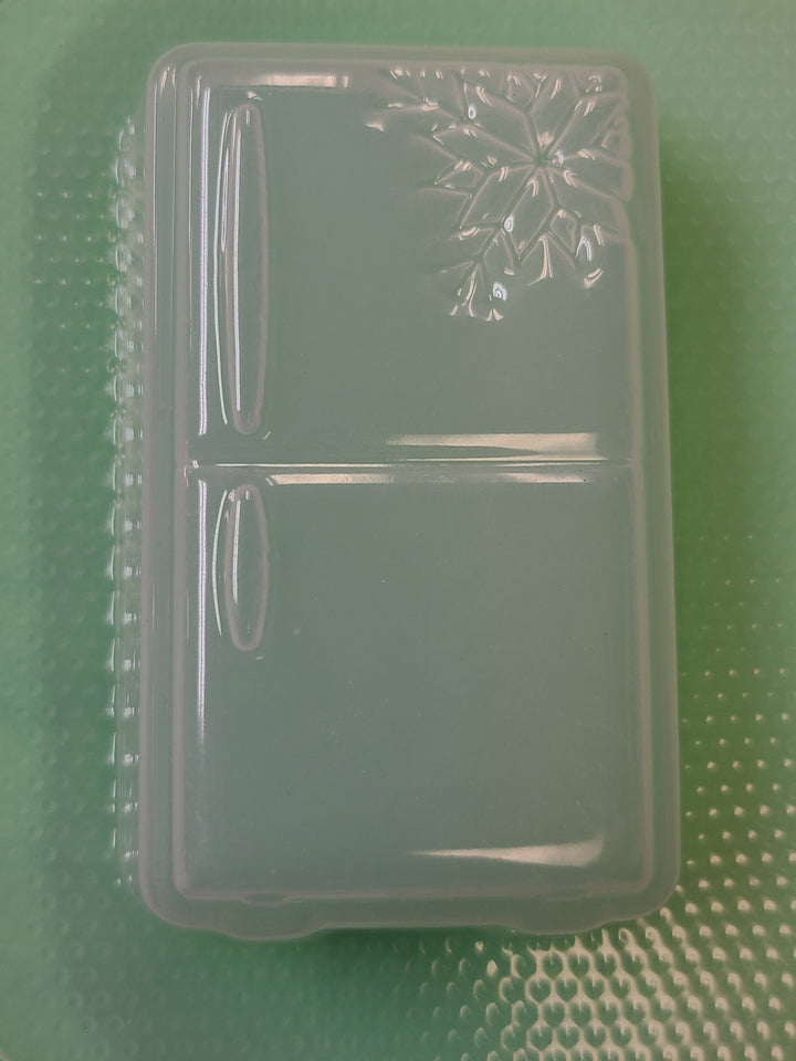 Clear plastic refrigerator mold on a green dimpled sheet, freezer door and handles cut in.