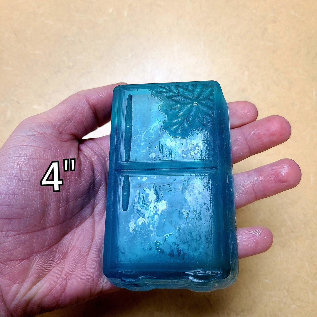 Translucent blue refrigerator cast held in a palm and marked four inches.