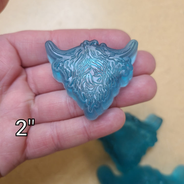 Blue highland cow cast at two inches held in a palm, fringe and horns clearly moulded.