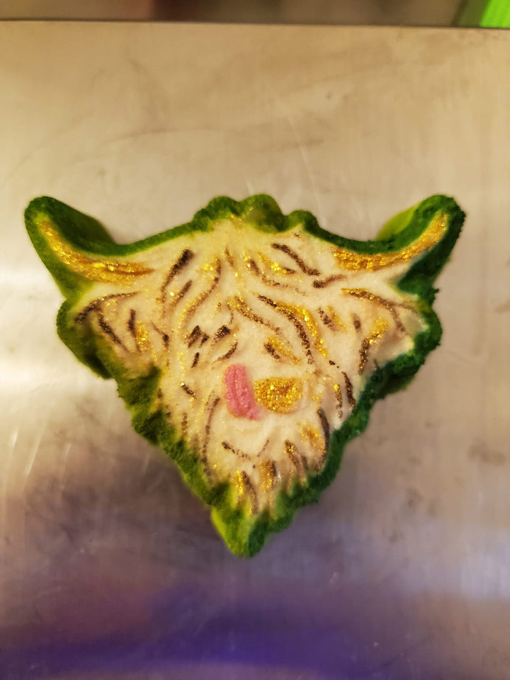 Highland cow head cast painted green and gold with a pink nose, shaggy fringe over the eyes.