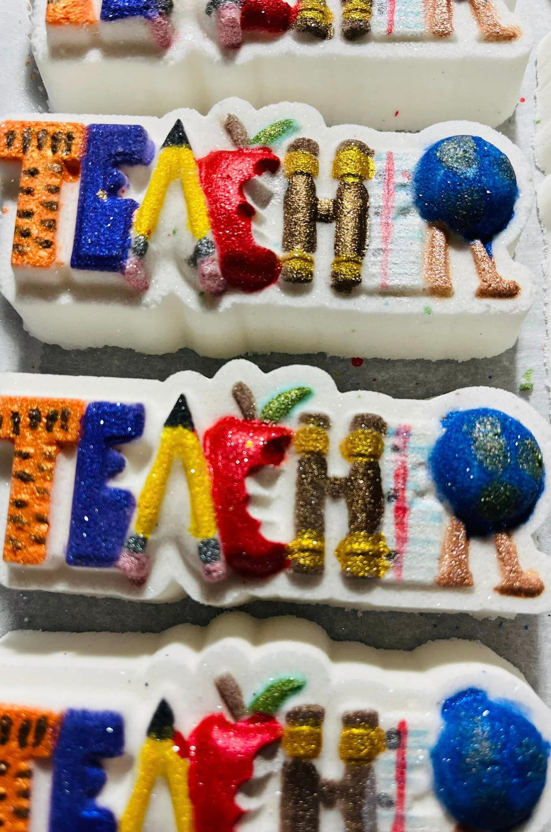Close view of painted TEACHER casts showing the pencil, apple, crayons and globe letters.