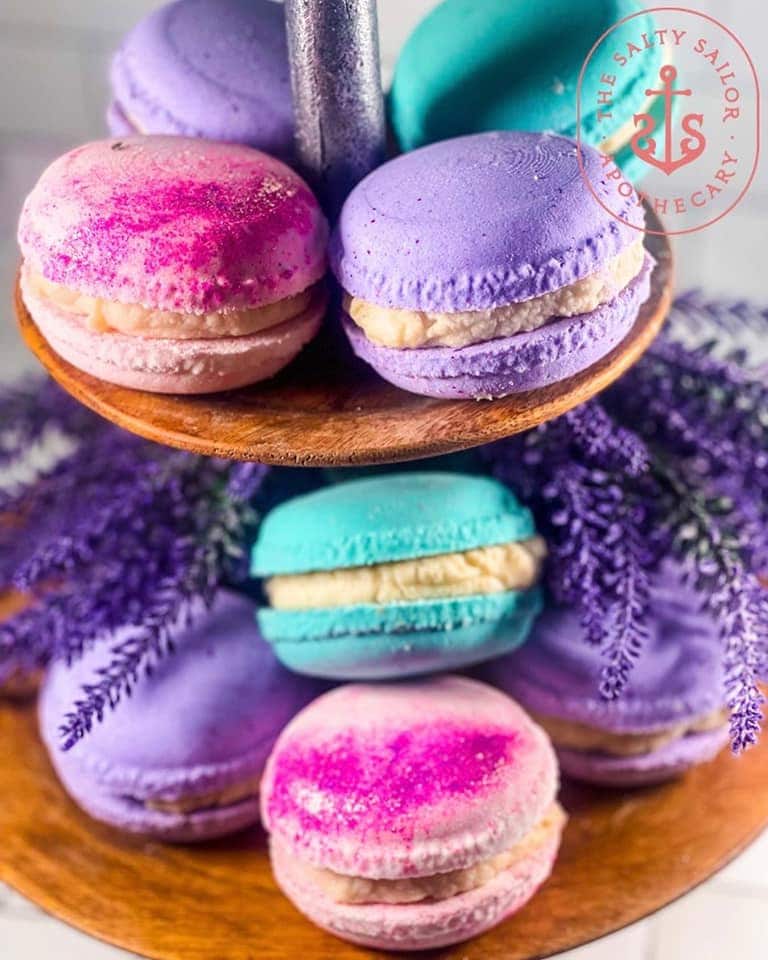 Stacked macarons in purple, pink and teal on a wooden riser with lavender behind.