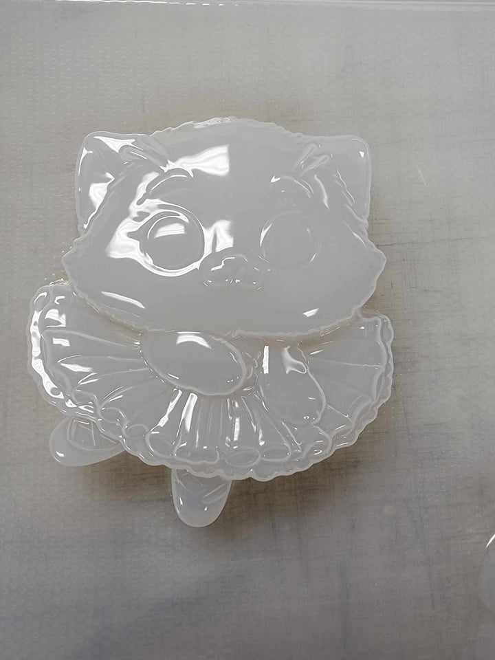 Clear plastic ballerina kitten mold, cat in a ruffled tutu on a plain grey background.