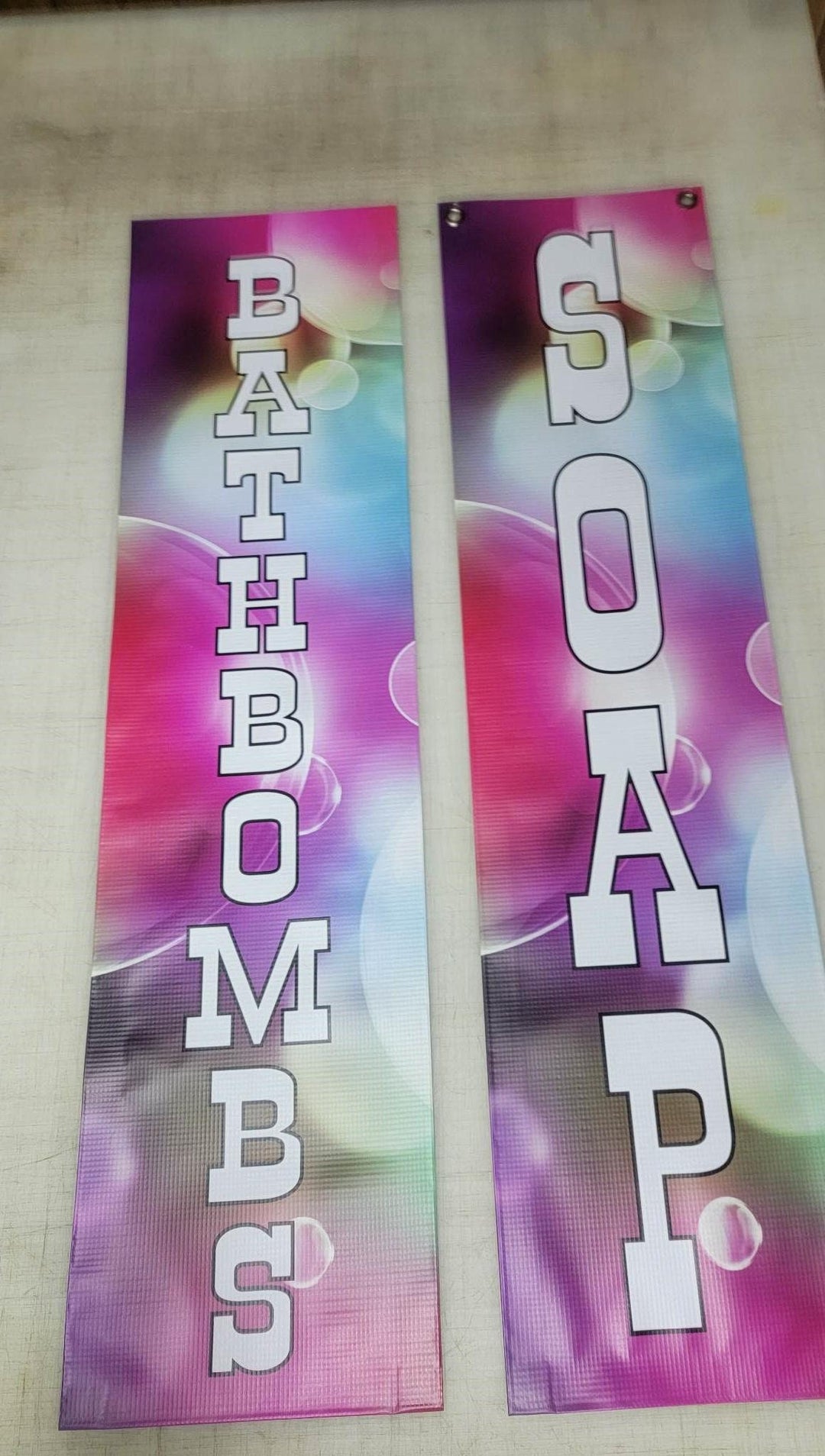 Two vertical banners reading BATHBOMBS and SOAP in white letters on a pink tie-dye ground.