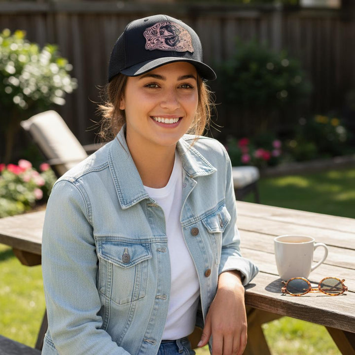Woman at a picnic table wearing the black cap with the rose-gold Rottweiler patch.
