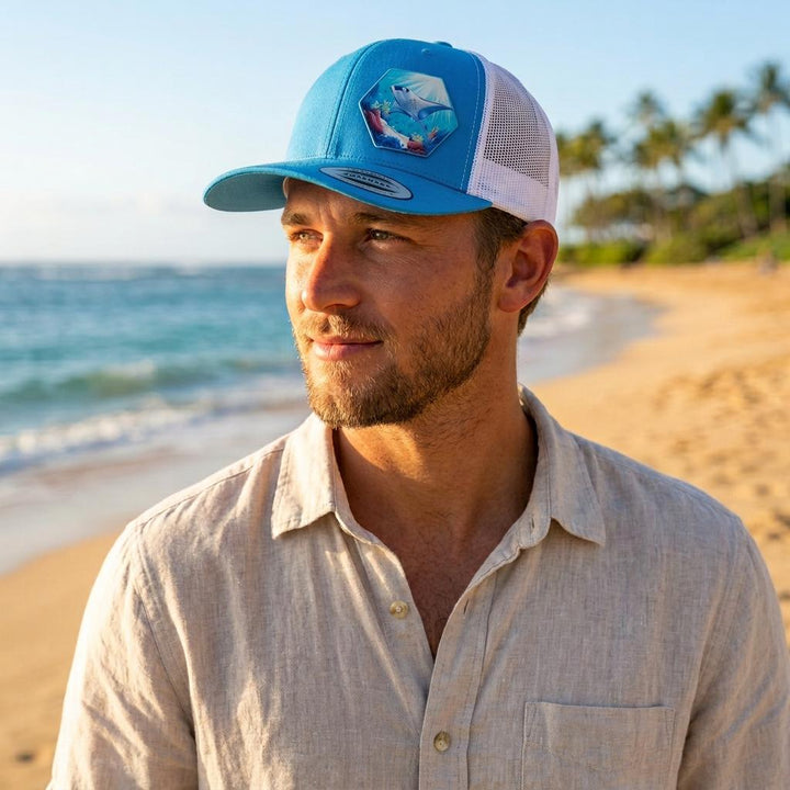 Man on a palm-lined beach wearing the blue manta ray snapback with white mesh back.