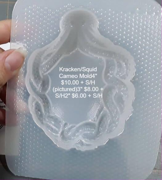 Clear plastic squid cameo mold, pointed mantle above tentacles curling round the oval frame