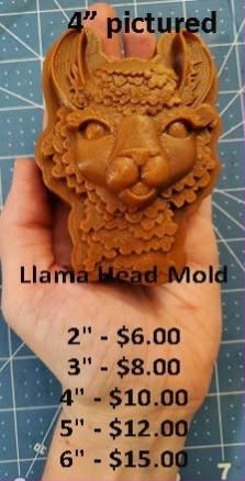 Caramel llama head casting with tall ears and a curled fleece forelock, held in a hand