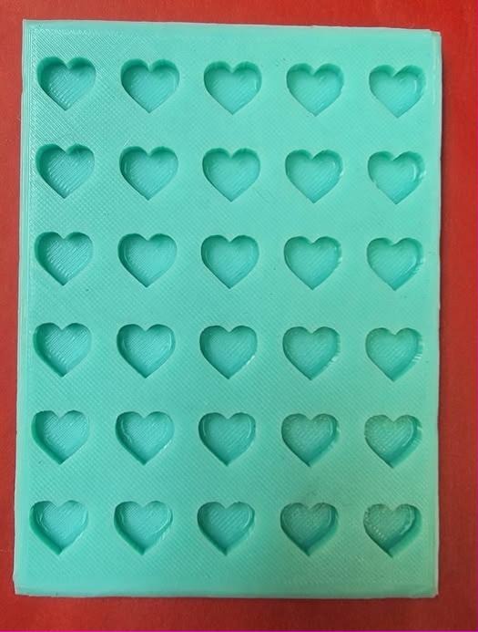 Flat silicone tray mold holding thirty small plain heart cavities laid out in six rows of five.