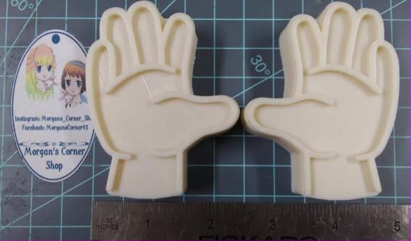 Pair of cream cast left and right open hands laid beside a ruler on a cutting mat