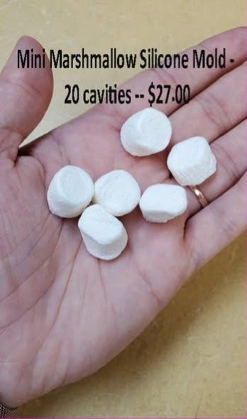 Hand holding six small white cast marshmallows from a twenty cavity marshmallow mold