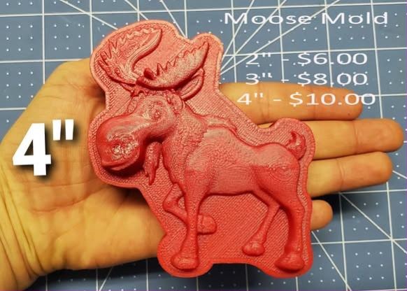 Coral red cast of a standing bull moose with antlers, held in an open hand