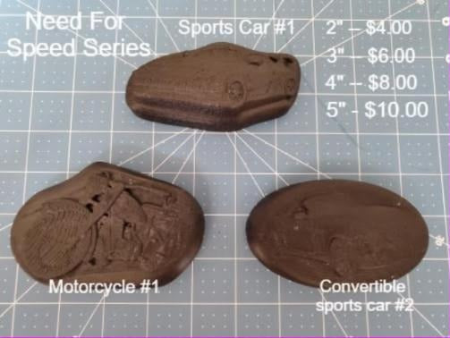 Three brown vehicle molds on a cutting mat: sports car, convertible and motorcycle in low relief.