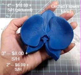 Blue resin orchid bloom cast held in a hand, broad petals around a ruffled centre lip.