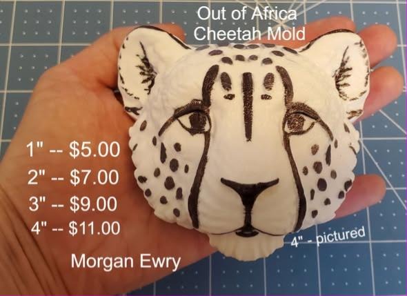 White cheetah face mold hand-painted with black tear lines, spots and whisker dots, held in a hand.