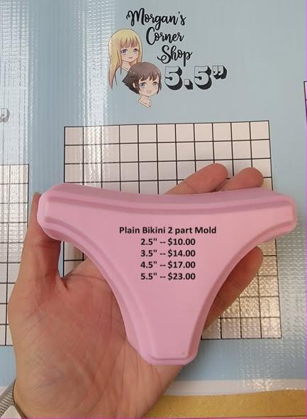 Pale pink cast of a plain bikini bottom with a low waistband and high-cut legs, held in a hand