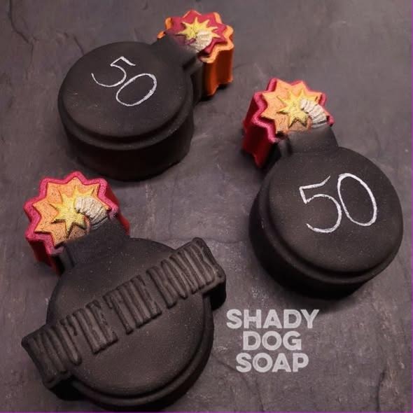 Round cartoon bomb soap casts with fuse necks and starburst sparks, shown in black on slate.