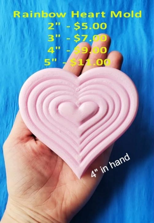 Pale pink cast of a heart made from six nested concentric heart ridges, held in a hand.