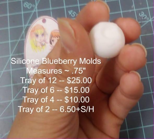 Small pale round blueberry cast held in a hand over a green cutting mat.