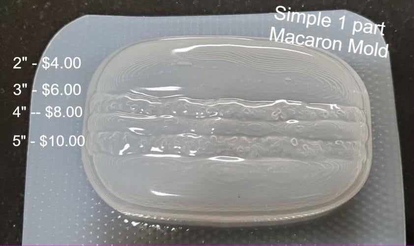 One part macaron mold with two domed shells, a ruffled foot frill and a filling band between.