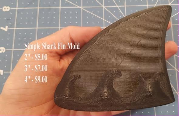 Brown printed master of a shark dorsal fin with wave curls at the base, held in a hand