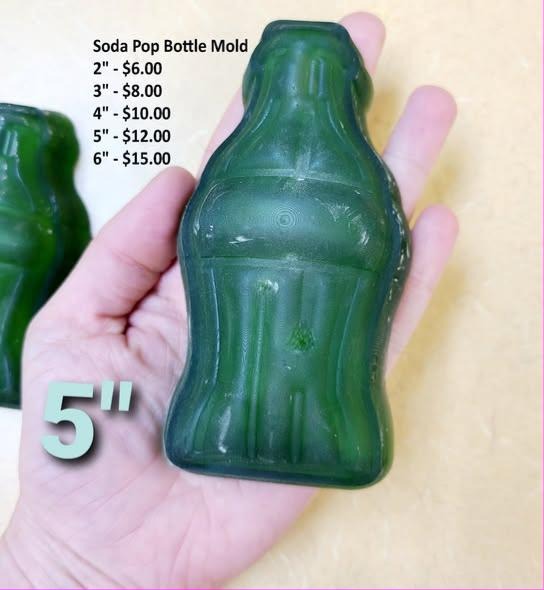 Deep green soda bottle cast with a fluted waist, flared crown top and ribbed sides, in a hand.