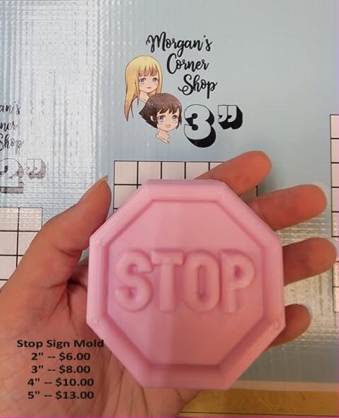 Pale pink octagonal stop sign cast with a raised rim and STOP in block capitals, held in a hand.