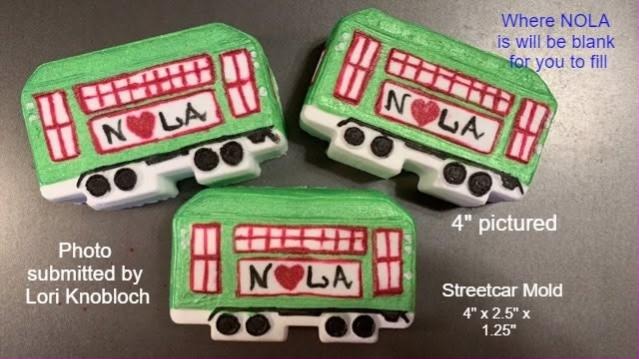 Three painted streetcar casts with red window frames and NOLA lettered on the side panel