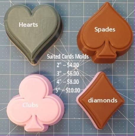 Four card suit molds on a cutting mat: green heart, orange spade, pink club and tan diamond.