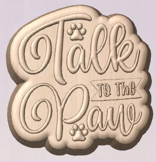 Pale wood tone cast of a Talk to the Paw mold in script lettering with small paw prints.