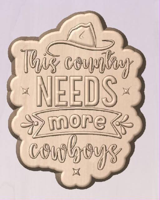 Wood tone cast of a scalloped plaque mold reading This country needs more cowboys with a hat.