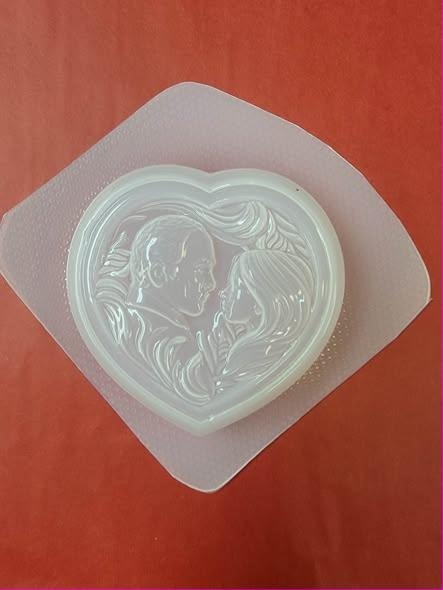 Heart-shaped plastic mold showing an older couple's profiles facing each other with flowing hair.