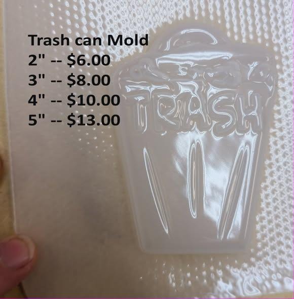 Clear plastic mold of a lidded trash can with TRASH lettered across the front.