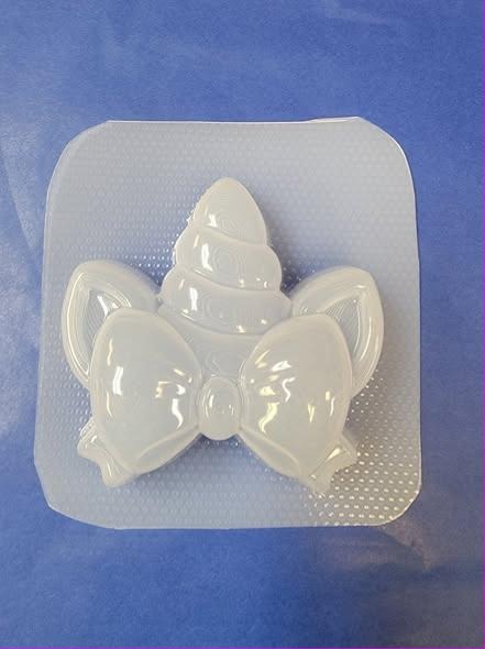 Clear plastic unicorn mold on blue, shaped as a spiral horn with two ears and a bow below.